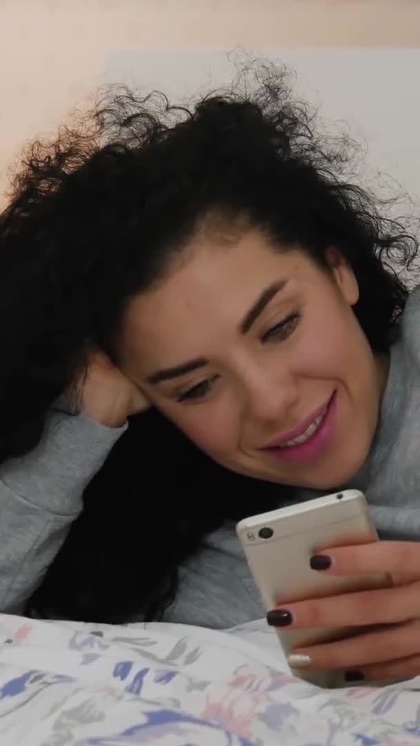 Κάθετη βίντεο από χαριτωμένο σγουρά γυναίκα χρησιμοποιώντας κινητό έξυπνο τηλέφωνο — Αρχείο Βίντεο