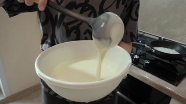 Sıcak bir mutfakta, insan bir kase malzemeyi karıştırır, lezzetli bir tarif yaratmak için gerekli olan karıştırma işlemini gösterir, mutfak sanatlarında yemek hazırlama tekniklerini gösterir.