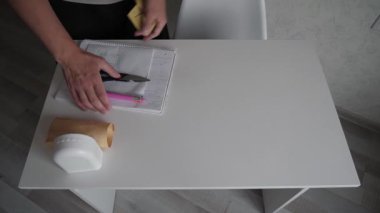 Tanınmayan bir adam beyaz bir masayı siler, temizler ve masayı bez parçasıyla siler.