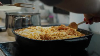 Rich Suce 'la spagetti pişiriyorum. Kadın eli makarnayı ustalıkla tavada karıştırır.