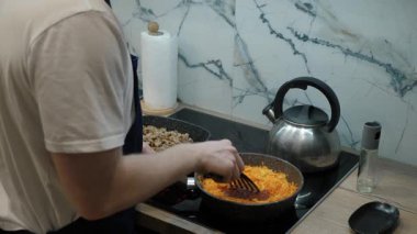 Baharatlı rendelenmiş havuçlar, sıcak atmosferde et ve sebzelerin pişirildiği sıradan mutfak sahneleri. Akşam yemeği pişirirken sobada renkli sos hazırlayan kişi.