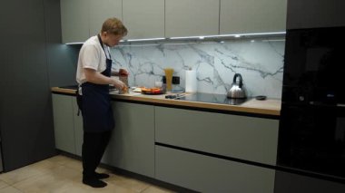 Şef metal rendeleyiciyle taze bir havucu rendeliyor, yetenekli bir adam modern bir mutfakta sağlıklı malzemeler hazırlıyor.