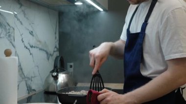 Genç bir şef, modern bir mutfakta leziz bir yemek hazırlarken etkileyici mutfak becerileri sergileyerek kıyma yapıyor.