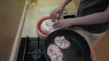 Kızartma için pirzola hazırlama, et dilimleri kaplama ve mutfakta pişirme, sobanın üstünde cızırdayan ev yapımı domuz pirzolası, sıcak yağda kızartılmış domuz eti ve cızırtılı ev yapımı mutfak sahnesi.