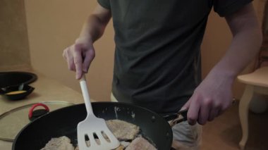 Spatula ile domuz pirzolası kızartan adam, ev mutfağı yakın çekim eller ve gövde, tava, odaklanmış hareket ve basit yemek hazırlığı
