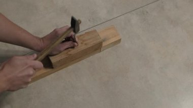 Ahşap işçiliği. Bir zanaatkar çekiç kullanır. Adam tahtaya çivi çakmaya odaklanmış.