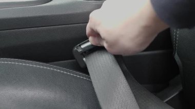 Sürücü kemeri mandala bağlıyor. Arabanın içi, emniyet kemeri tokası ve emniyet özellikleriyle dolu. Emniyet kemeri tokası bağlama işleminin aracın içindeki güvenlik önemine vurgu yapılmıştır.