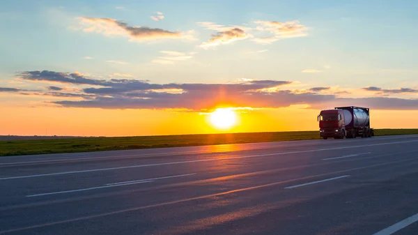 Truck moving on high-speed highway at sunset.