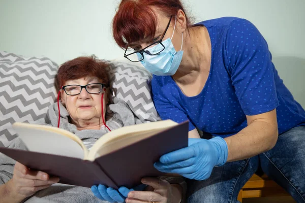 Старша Жінка Читає Книгу Медсестрою Хвора Старша Жінка Лежить Ліжку — стокове фото