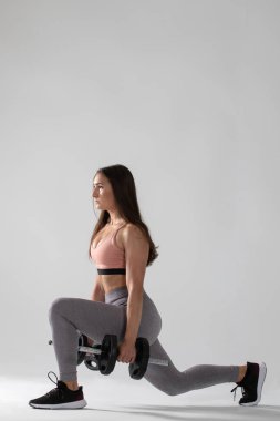 Beyaz arka planda dambıllarla egzersiz yapan güzel bir genç kadın, ağırlıklarla spor yapan genç bir kadın. ,