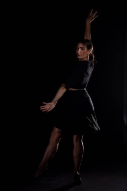 Genç profesyonel dansçı stüdyoda çalışıyor, siyah elbiseli genç kadın dans ediyor, dansçı.