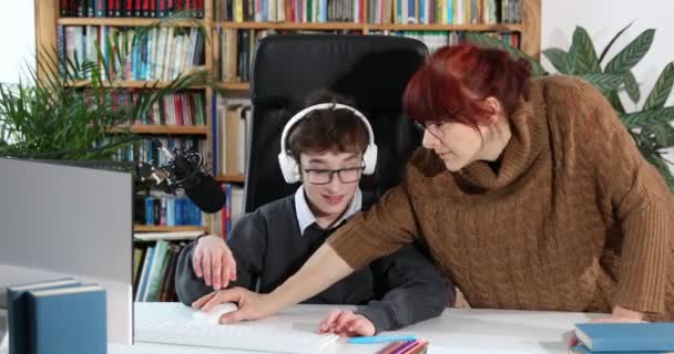 可爱的男孩和妈妈在家做作业 妈妈帮儿子 教如何做作业 概念教育 男中学生被隔离 戴眼镜的有爱心的母亲帮助男孩在家里的电脑上做作业 — 图库视频影像