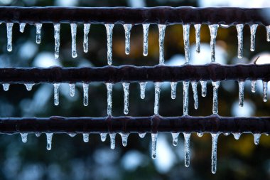 Kışın birçok küçük buz sarkıtları. Kahverengi bir borudan sarkan buz saçakları. Donmuş su ve metal yüzey, kış zamanı konsepti