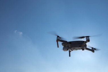 Mavi gökyüzünde uçan dron, güneş ışığında uçan drone