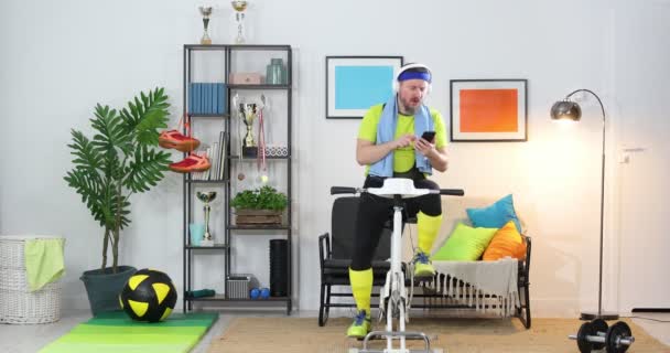 Uomo Sano Allena Casa Una Cyclette Statica Mentre Allena Tenendo — Video Stock
