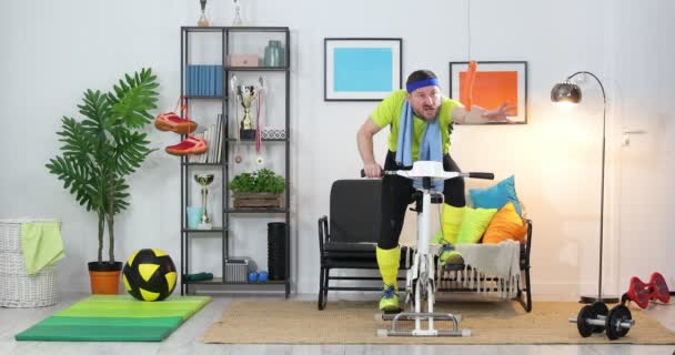 Ung Mand Atlet Stationær Cykel Udøver Derhjemme Fitness Parodi Humor – Stock-video