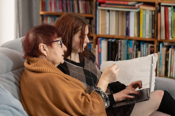 Young woman teaching grandmother to do online shopping. Grandmother and granddaughter shopping online.