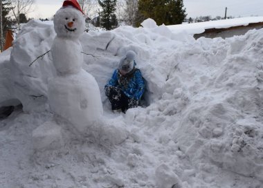 Bir çocuk bir kardan adamla oynuyor.