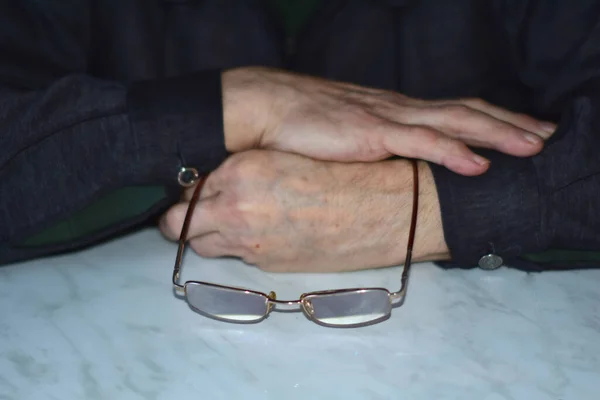 Hände Und Brille Des Alten Mannes Auf Dem Tisch — Stockfoto