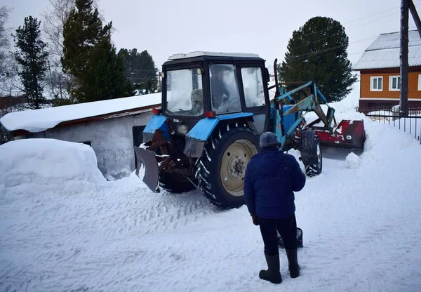 tractor removes snow in the yard, winter day