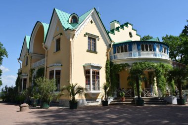 Parktaki binanın ön cephesi, bir yaz günü, insanların dinlenebileceği bir yer.