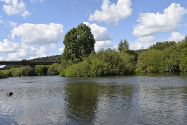 Nehir, yeşil kıyılar, bulutlu gökyüzü