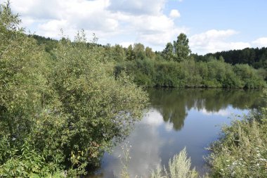 Nehir, yeşil kıyılar, bulutlu gökyüzü