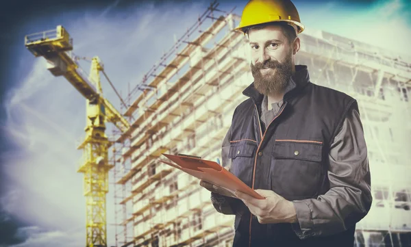 Smiling worker with protective uniform in front of construction