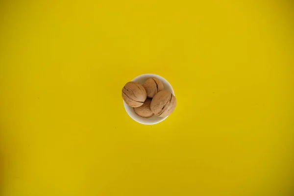 walnuts on a yellow solid background. Food background. Kitchen. white plate. top view