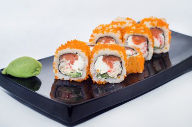 Sushi ginger ve wasabi ile siyah bir plaka üzerinde rulo