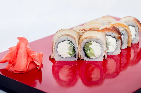 Filadelfia rollo con anguila en un plato rojo con reflexión sobre un fondo blanco — Foto de Stock