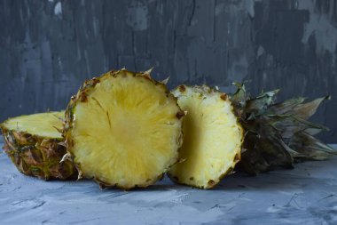 Gri arka planda yeni kesilmiş bir ananas yatay olarak yer almaktadır.