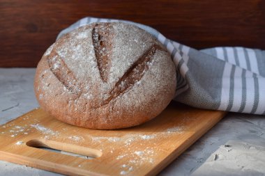 Tahtada taze pişmiş çavdar ekmeği, pamuk peçete, yazı için bir yer. Gri arkaplan, yakın plan