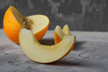 Yarım sarı kavun grisinin arka planında taze sulu tatlı bir kavun dilimi