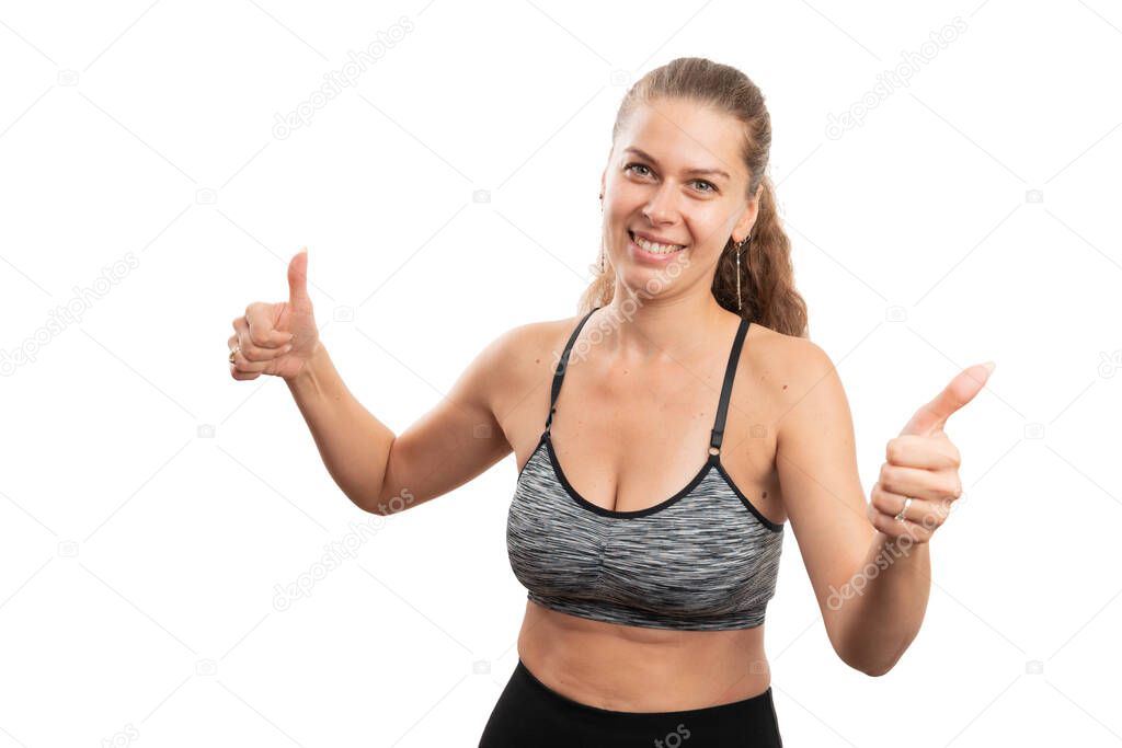 Athletic friendly female model in gym fitness attire showing double like gesture using thumbs as sportive lifestyle concept isolated on white background