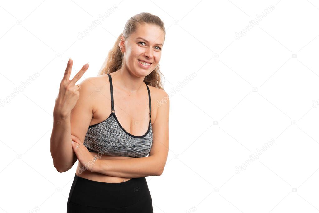 Smiling athletic adult woman wearing workout training gym attire making number two gesture using fingers as counting and healthy lifestyle concept isolated on white background with blank copyspace