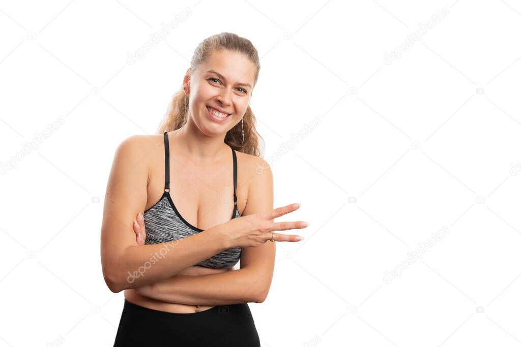 Friendly fit adult woman in gym fitness clothing showing number three with fingers as counting and active lifestyle concept isolated on white background with copyspace for adverting