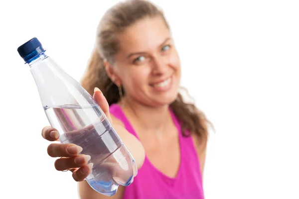 ピンクのスポーツウェアのタンクトップを身に着けている大人の女性が笑顔で提示した水ボトルのクローズアップ健康的な水分補給ドリンクコンセプトとして選択的白の背景に隔離された — ストック写真