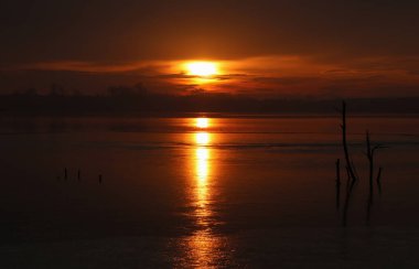 Ocak ayında donmuş bir gölün üzerinde romantik bir gün doğumu