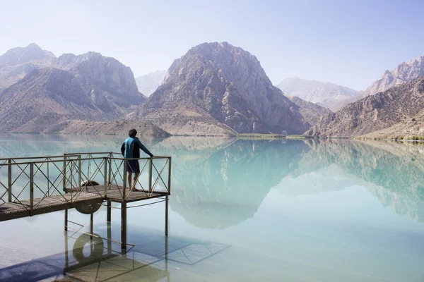 年轻人坐在长椅上附近山湖 Iskanderkul，中心 图库图片