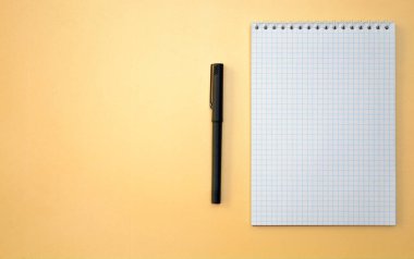 Sarı arkaplanda not defteri ve kalem.