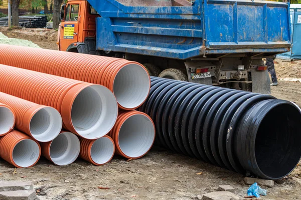 Lviv, Ukrayna - 24 Ekim 2020: Yeni turuncu plastik kanalizasyon boruları açık havada bulunmaktadır. Farklı çaplarda boruları olan bir inşaat alanı. 