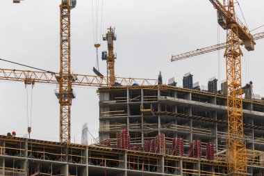 Yüksek katlı vinçleri olan bir inşaat alanı. Modern apartmanlar ve yeni bir konut kompleksi inşaatı.