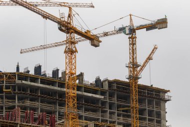 Yüksek katlı vinçleri olan bir inşaat alanı. Modern apartmanlar ve yeni bir konut kompleksi inşaatı.