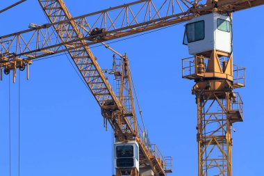 Yüksek katlı vinçleri olan bir inşaat alanı. Modern apartmanlar ve yeni bir konut kompleksi inşaatı. Mavi gökyüzü.