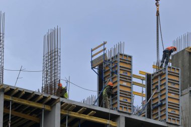 Kyiv Ukrayna - 16 Mart 2021: Bir inşaat sahasının en üst katında bir grup üst düzey toplayıcı çalışıyor. Modern apartmanlar ve yeni bir konut kompleksi inşaatı. Mavi gökyüzü.