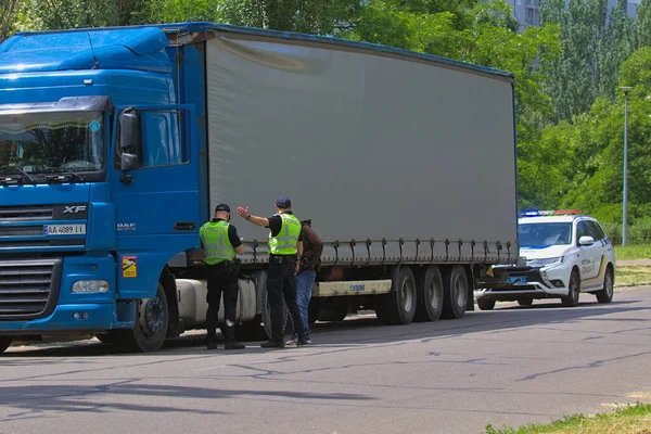 Kyiv Ukrayna - 11 Haziran 2021: Sağlık maskesi takan iki polis koronavirüs nedeniyle karantina sırasında otoyolda bir arabayı kontrol etti. Sürücü belgelerini kontrol ediyorum. Sokak fotoğrafı..