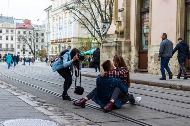 Lviv, Ukrayna - 24 Ekim 2020: Bir grup fotoğrafçı, eski şehrin antik caddesinde genç bir adamla genç bir kadının sarılıp öpüşmelerini fotoğraflıyor. Sokak kültürü.