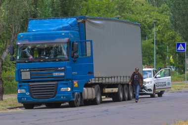 Kyiv Ukrayna - 11 Haziran 2021: Sağlık maskesi takan iki polis koronavirüs nedeniyle karantina sırasında otoyolda bir arabayı kontrol etti. Sürücü belgelerini kontrol ediyorum. Sokak fotoğrafı..