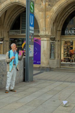 Münih, Almanya - 22 Ekim 2024: Tanımlanamayan bir adam Münih 'in göbeğindeki hareketli Marienplatz' da bir arya söylüyor. Tarihi Yeni Belediye Binası ve renkli cepheler meydanı çerçeveliyor.